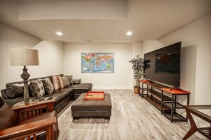 Una sala de estar moderna con un sofá, un reposapiés y una mesa larga.
