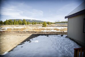 A building with a snow-covered ground and a view of a forested area with mountains in the background. - 4BR Mountain Home | Fireplace, King Beds, Fast Wi-Fi (Leadville)