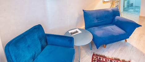 A modern living room with two blue sofas, a small round table, and decorative wall art.
