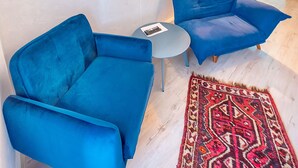 Un soggiorno moderno con due divani blu, un tavolino rotondo e un tappeto decorato.