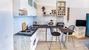 Una cucina compatta con fornello, lavandino e un piccolo spazio pranzo con due sedie.