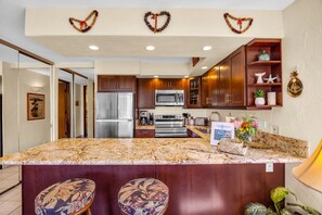 A kitchen with a central island, wooden cabinets, stainless steel appliances, and a decorative heart garland on the ceiling.