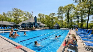Une piscine avec des couloirs de nage, des chaises longues et un espace abrité avec des parasols.