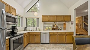 Une cuisine moderne avec des meubles en bois, des appareils électroménagers en acier inoxydable et une grande fenêtre qui laisse entrer la lumière naturelle.