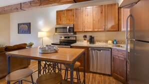 A modern kitchen with wooden cabinets, stainless steel appliances, and a wooden dining table with stools. - 2 Bd 1.5 Ba Condo close to main street in Frisco, CO! (Frisco)