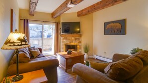 A cozy living room with a fireplace, wooden beams, a sofa, and a lamp. - 2 Bd 1.5 Ba Condo close to main street in Frisco, CO! (Frisco)