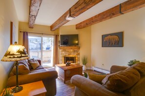 A cozy living room with a fireplace, wooden beams, a sofa, and a lamp.