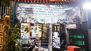 Ein Geschäft mit einer Schautafel, die Dienstleistungen wie Friseurbesuche und Nagelpflege sowie Motorradvermietung anbietet.