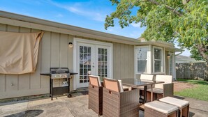 An outdoor patio with a grill, wicker furniture, and a covered area.
