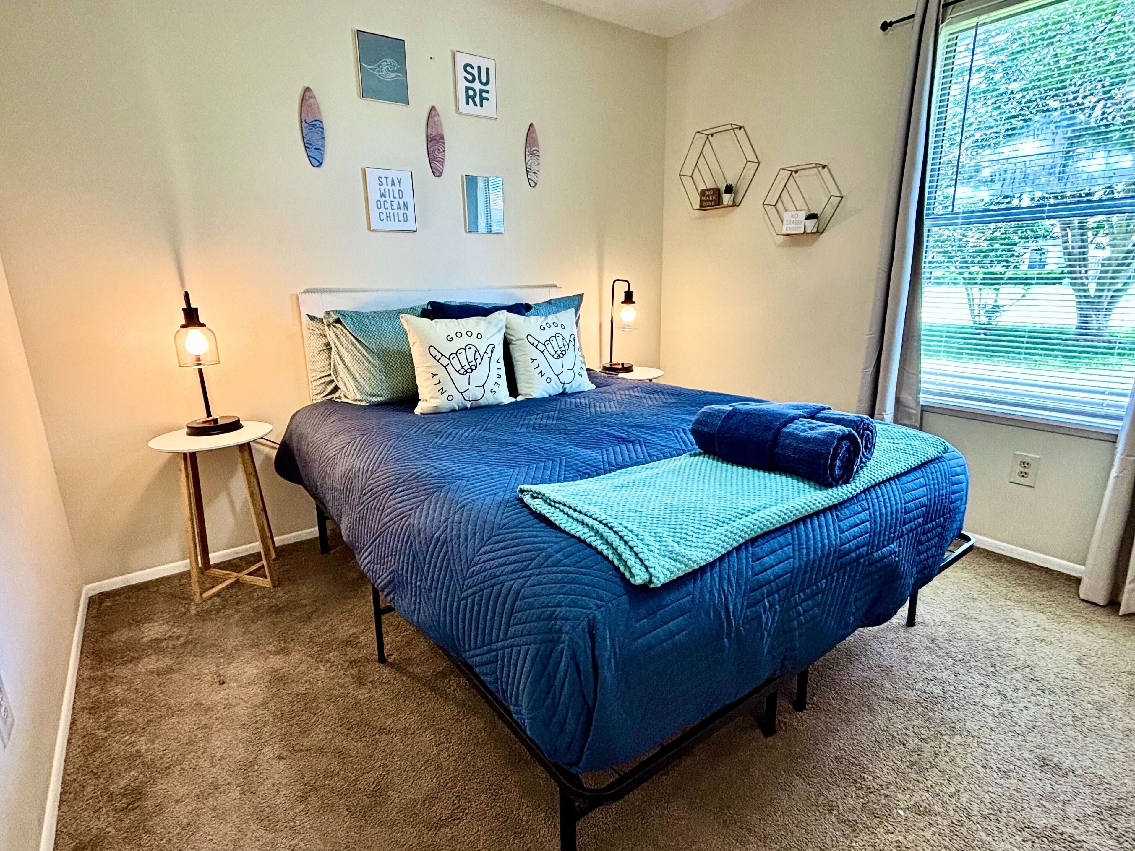 Een slaapkamer met een bed, twee nachtkastjes, een raam met zonwering en decoratie aan de muur.