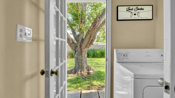 A laundry room with a washing machine and a sign above the door that reads "Lost Socks Seeking Sole Mates".