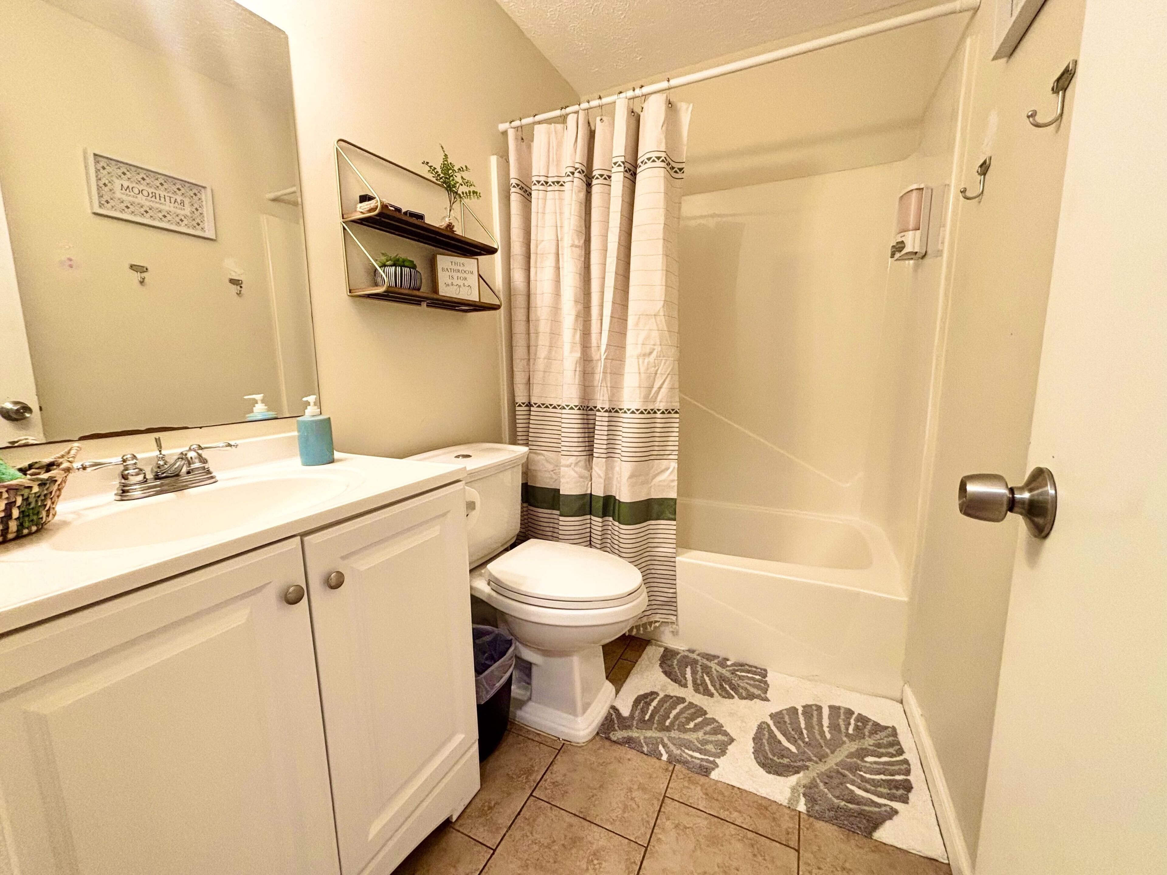 A bathroom with a toilet, sink, and shower curtain.