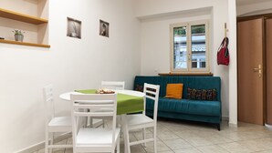 Un espacio habitable compacto con zona de comedor, sofá y ventana con vista a un edificio.