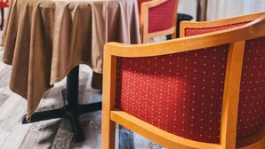 Habitación de hotel con una mesa redonda, dos sillas, un televisor montado en la pared y una planta en maceta.