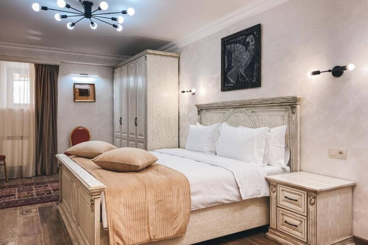 Un dormitorio con una cama grande, una mesita de noche, un armario y una lámpara en el techo.