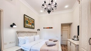 Un dormitorio con cama, mesitas de noche, una araña, un cuadro y un armario.