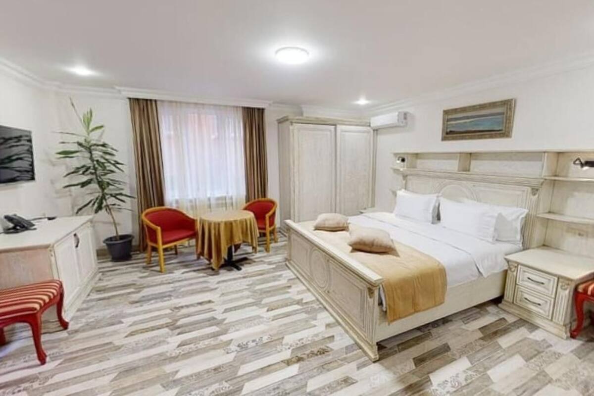 Una habitación de hotel con cama, escritorio, silla, mesita y televisor.