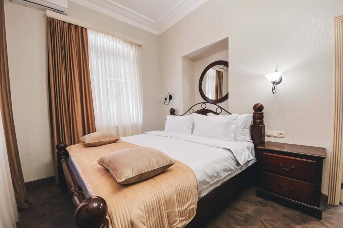 Un dormitorio ordenado con cama, mesita de noche y un espejo en la pared.