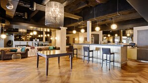 A modern bar area with a wooden floor, bar stools, and pendant lighting.