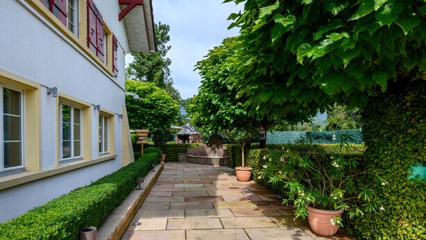 A stone pathway leading to a building with a white facade and red shutters. - Apart-Hôtel Pont-de-Thielle (Gals)