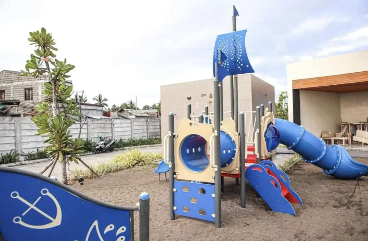 A playground with a slide, climbing structure, and a flag.