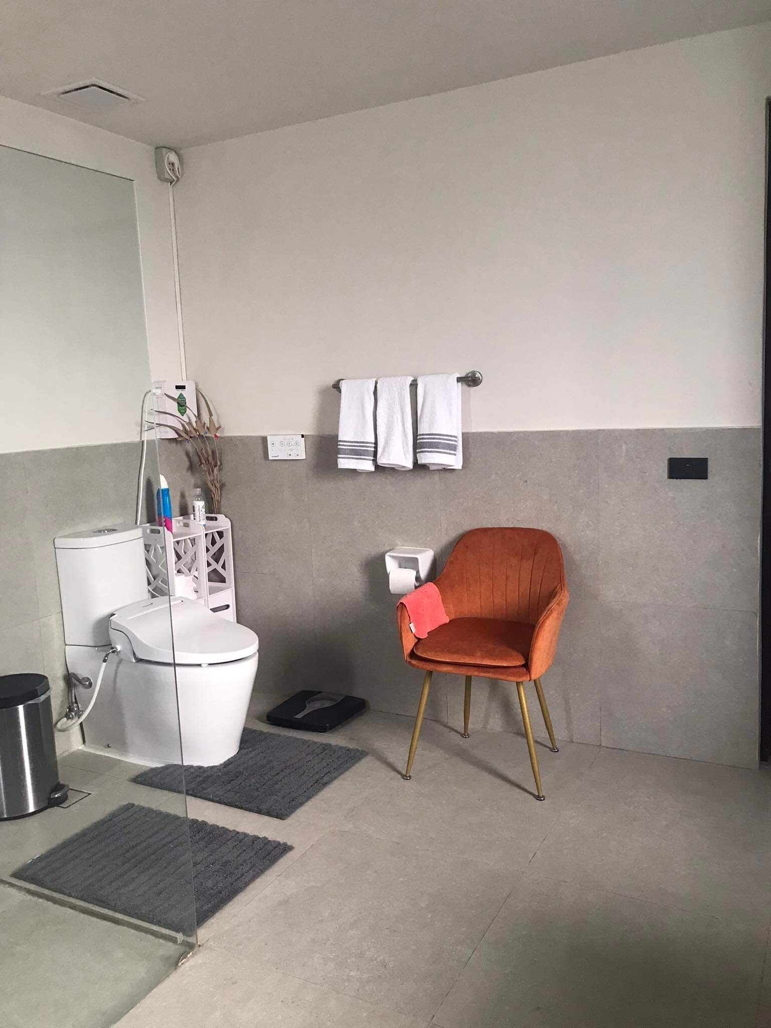 Moderni kylpyhuone, jossa on wc, bidee ja tuoli.
