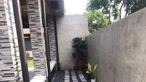 Un sendero estrecho con piedras para pisar, rodeado de plantas en macetas y una pequeña zona de césped.
