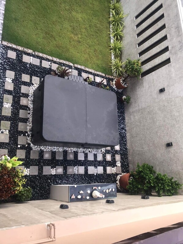 A modern outdoor seating area with a built-in bench, surrounded by a pebble-patterned border, potted plants, and a concrete wall.