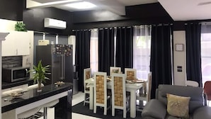 Una cocina moderna con comedor, con una decoración en blanco y negro, un refrigerador, microondas y una mesa de comedor con sillas.