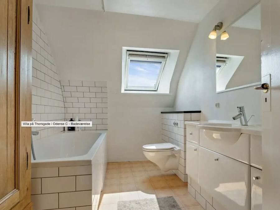 A bathroom with a bathtub, toilet, and vanity with a mirror.
