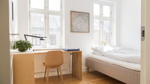 Un dormitorio con cama, escritorio, silla y radiador.