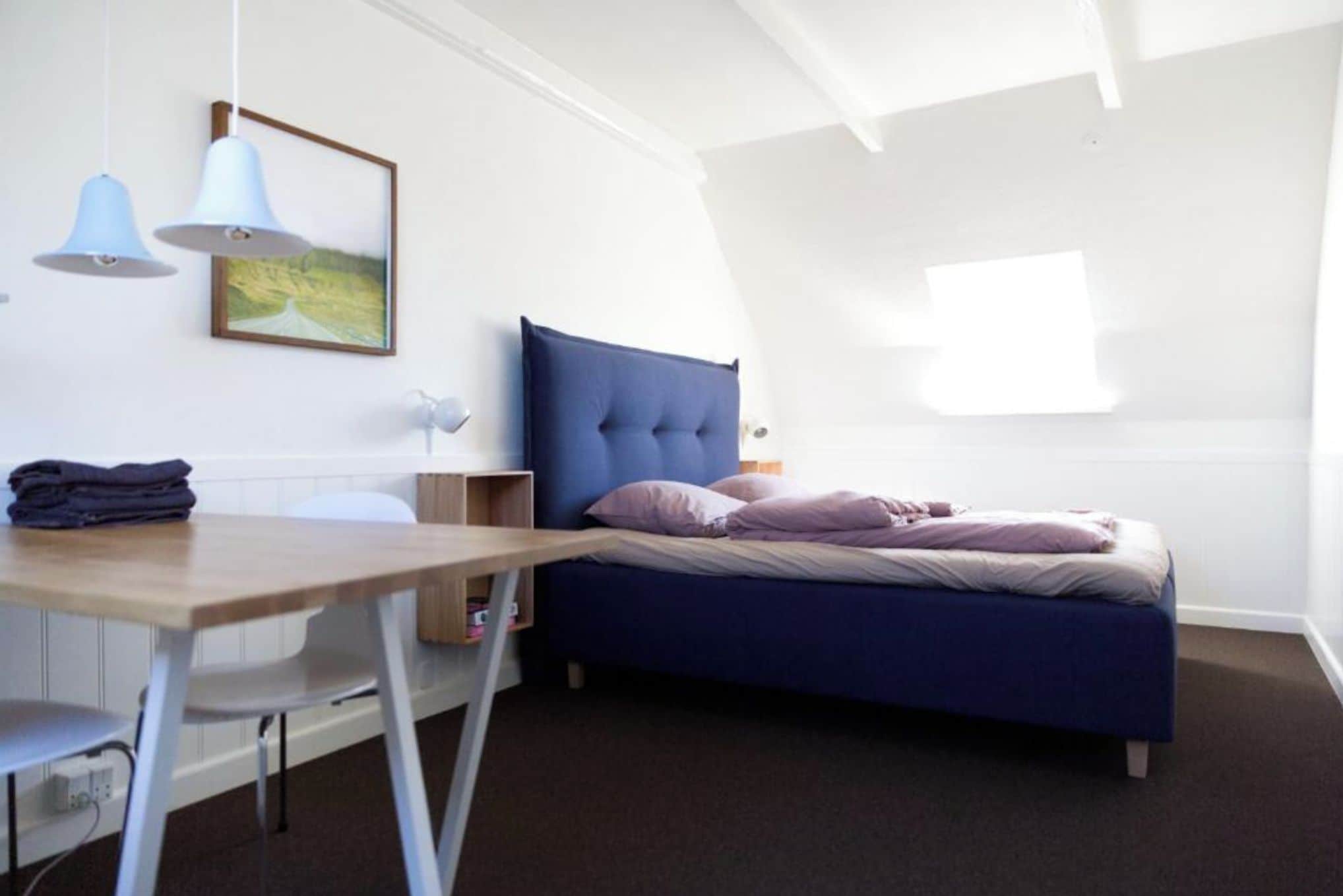 Een slaapkamer met een bed, een bureau, een stoel en een raam.