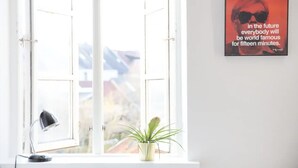 Una habitación con un ventanal grande, un escritorio con una lámpara y una planta en maceta.
