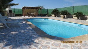 A swimming pool with a tiled deck, surrounded by potted plants and outdoor furniture. - Casa Bougainvillea
Relax by the pool, it is yours  for the length of your stay (Lorca)