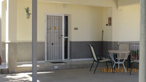A covered outdoor area with a white door, a chair, a small table, and a broom leaning against the wall. - Casa Bougainvillea
Relax by the pool, it is yours  for the length of your stay (Lorca)