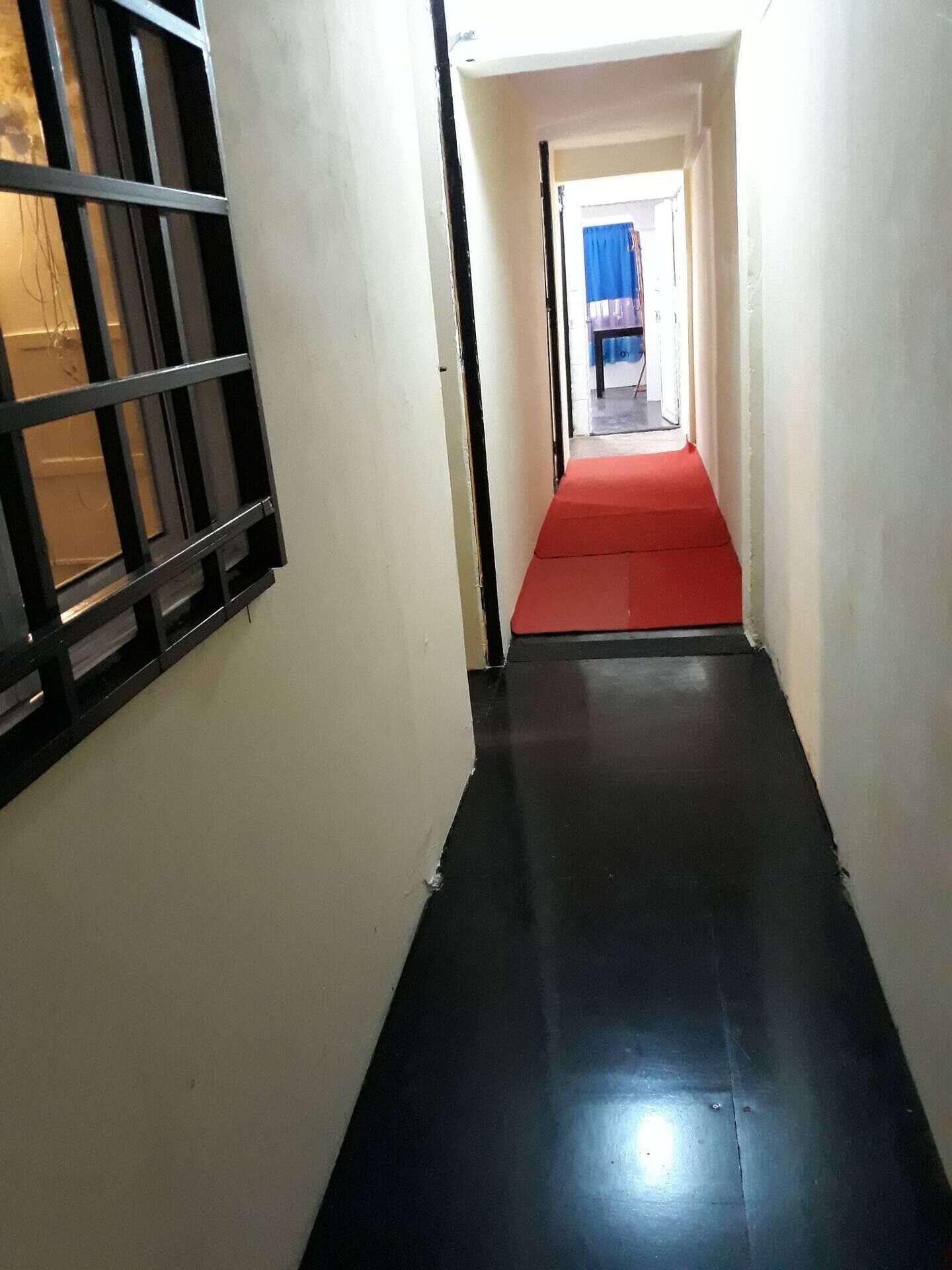 A narrow hallway with a red carpet leading to a room.
