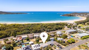 Vista aérea de una zona residencial costera con casas, una playa y una gran masa de agua.