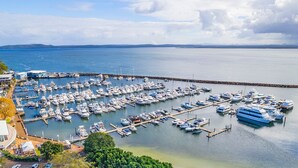 Un port de plaisance où sont amarrés de nombreux bateaux, une jetée et un bâtiment à la façade blanche.
