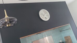 A kitchen with a black countertop, a stainless steel refrigerator, a coffee maker, and a clock. - Villa du Ridin - La Villa 4 Fleurs (Le Crotoy)