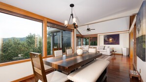 A spacious dining area with a wooden table, cushioned benches, and large windows offering a view of greenery. - Mountain View/Jacuzzi/ Fire pit/ Close to Downtown. Pet Friendly!  (Murphy)