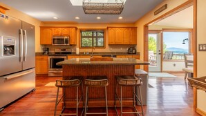 A modern kitchen with wooden cabinets, stainless steel appliances, and a bar area with stools. - Mountain View/Jacuzzi/ Fire pit/ Close to Downtown. Pet Friendly!  (Murphy)