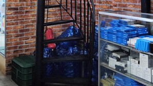 Un escalier avec un mur en briques, une rampe en métal et une vitrine contenant divers objets.