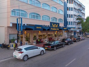 A hotel with a prominent 'Premium Inn' sign, multiple windows, and a parking area with several cars.
