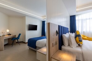 A hotel room with a bed, a desk, a chair, a TV, and a window with curtains.