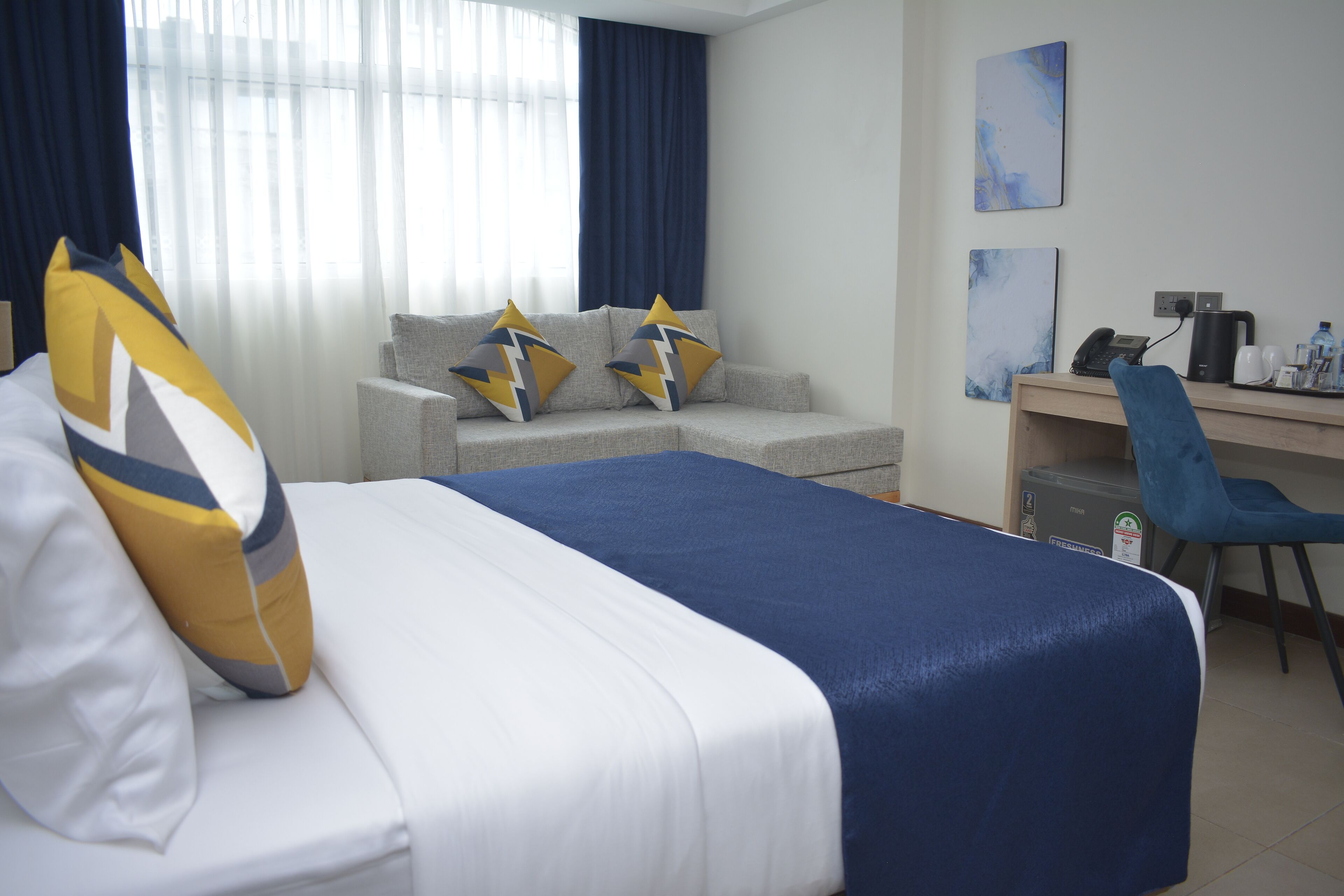 A hotel room with a bed, a desk, a chair, and a small table.