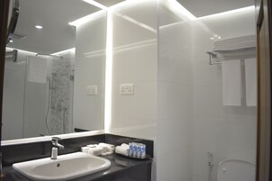 Un baño moderno con lavamanos, espejo y ducha blancos.