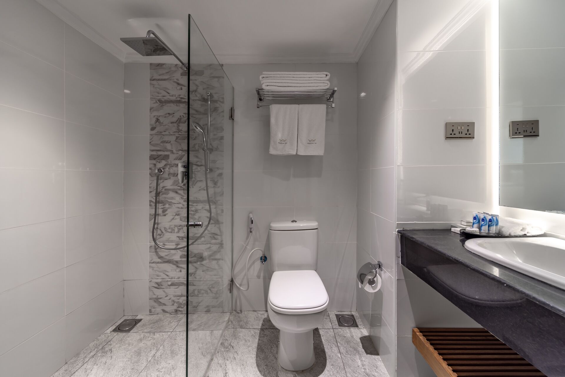 Un baño moderno con ducha envuelta en vidrio, inodoro y lavabo con tocador.