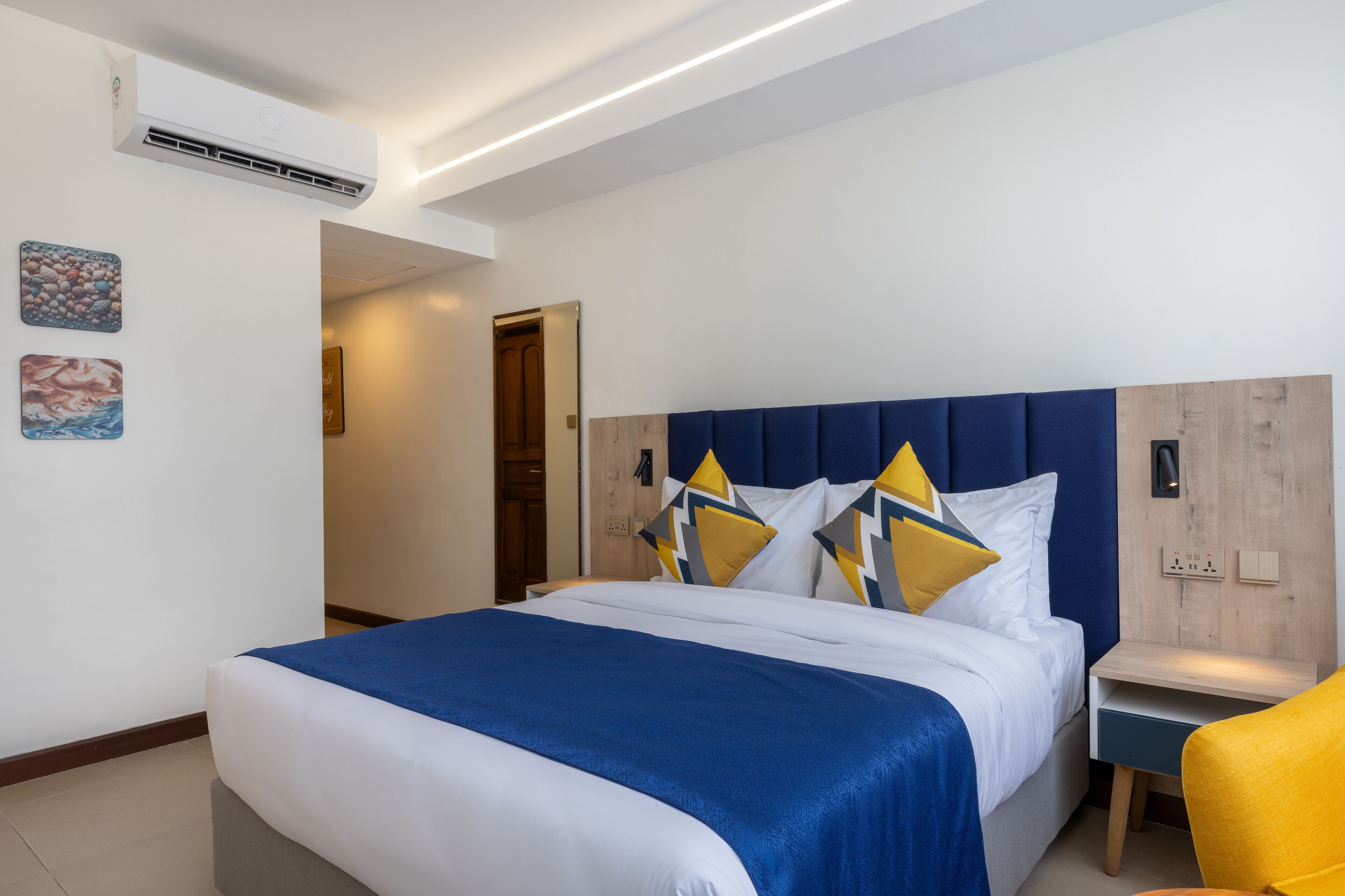 Ein modernes Hotelzimmer mit einem großen Bett, einem hölzernen Kopfteil und einem Nachttisch mit einer Lampe.