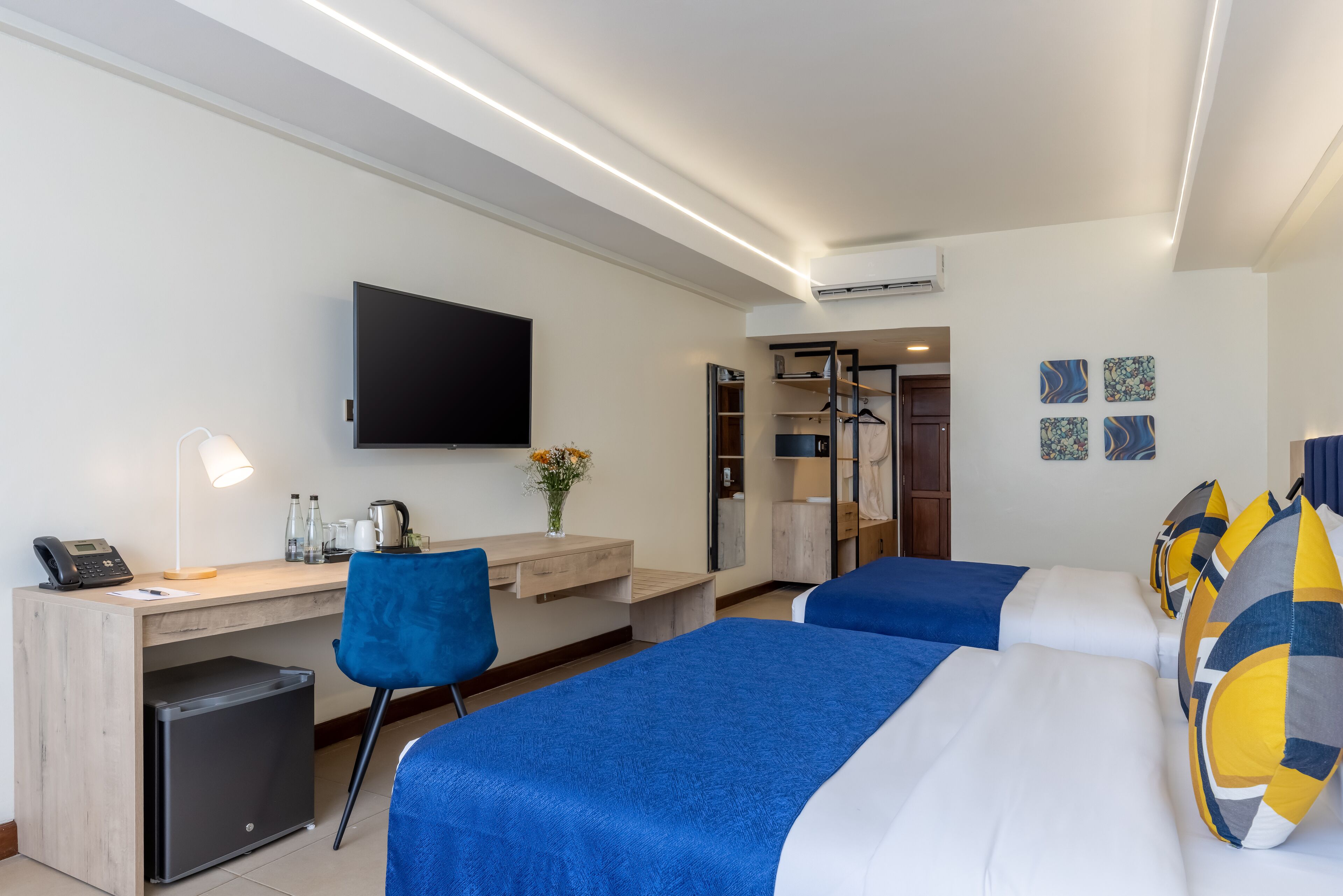 A hotel room with a desk, chair, two beds, a TV, and a wardrobe.