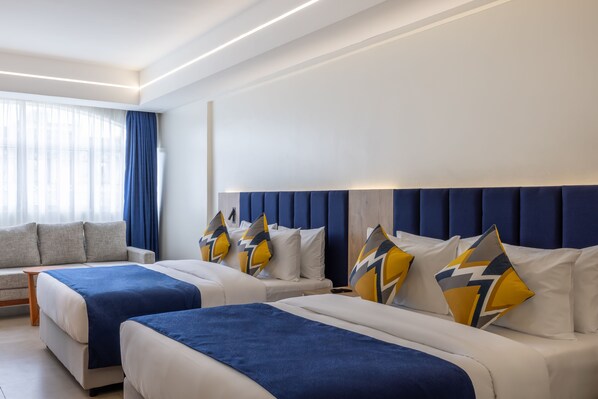 A hotel room with two beds, a sofa, and a large window with curtains. - Premium Inn (Mombasa)